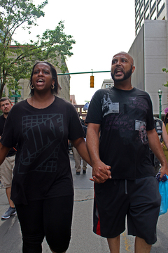 Couple Domonique Baldwin and Ronald Lee march with other Syracuse community members while holding hands and chanting.