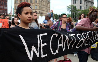 Syracuse University student Sarah Ibrahim holds a banner that says: 