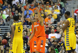 Michael Carter-Williams #1 of the Syracuse Orange points to signal possession as he stands on the ourt with Junior Cadougan #5 and Davante Gardner #54