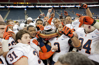 As one, Syracuse lifts the Texas Bowl trophy at midfield.