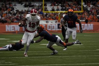 Wolfpack wide receiver Bra'Lon Cherry tries to slip a tackle by Syracuse safety Ritchy Desir as defensive end Donnie Simmons (51) trails.