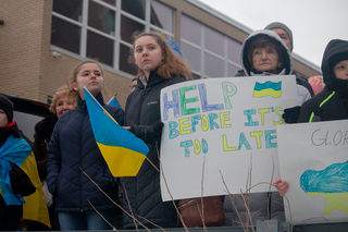 People hold posters and flags to raise awareness about the violence in Ukraine. 