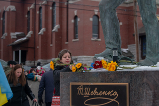People lay flowers at the feet of a statue outside of the Ukrainian church. 