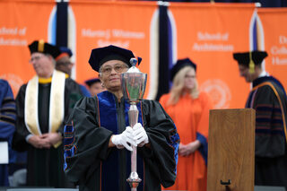 Bea González, the university mace bearer, enters the JMA Wireless Dome at the beginning of the ceremony. González previously served as dean of SU’s College of Professional Studies.  